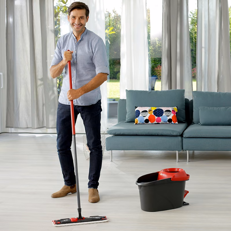 Wkład do Mopa Płaskiego Vileda Ultramax XL Microfibre 2w1, mężczyzna myjący podłogę w salonie mopem z wiadrem